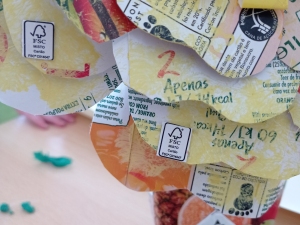 Flor elaborada das embalagens de Sumo Compal, destacando os símbolos da Tetra Pak e FSC.