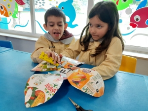 As crianças a colar a flor, onde se pode ver o selo da tetra pak