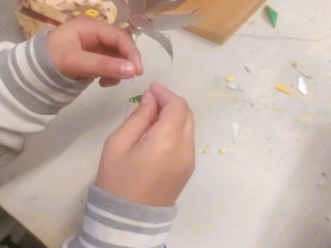 Processo de construção da flor. Colagem das pétalas e das folhas no caule de arame.